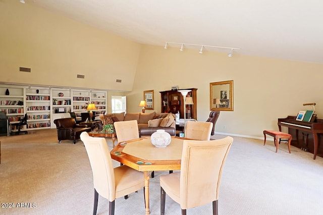 carpeted dining room with high vaulted ceiling and rail lighting