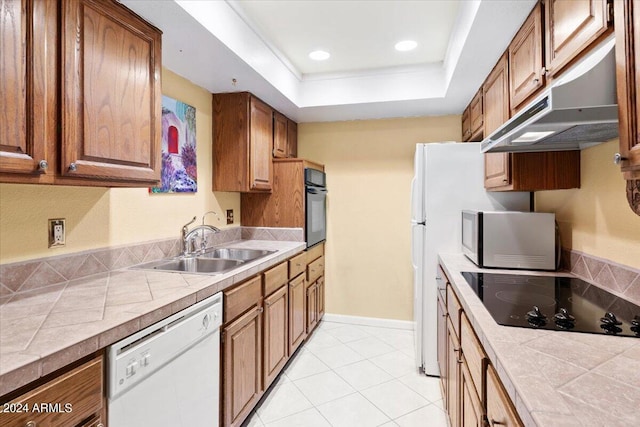 kitchen featuring a raised ceiling, sink, tile countertops, black appliances, and light tile patterned floors