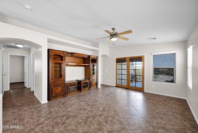 unfurnished living room with ceiling fan, french doors, visible vents, arched walkways, and baseboards