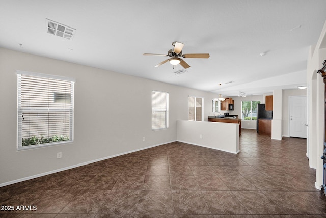 unfurnished living room featuring ceiling fan, baseboards, lofted ceiling, dark tile patterned flooring, and visible vents
