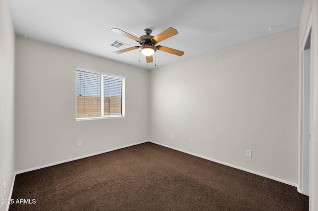spare room with baseboards, a ceiling fan, dark carpet, and visible vents
