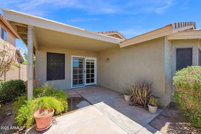entrance to property featuring a patio area, stucco siding, and fence