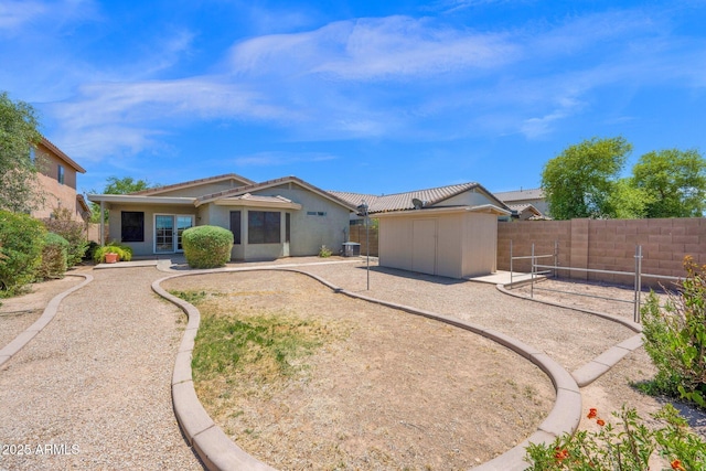 back of house featuring a storage shed, an outbuilding, a fenced backyard, and stucco siding