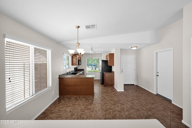 kitchen with visible vents, a sink, baseboards, freestanding refrigerator, and a chandelier