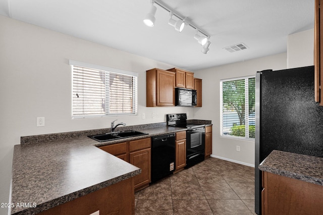 kitchen featuring visible vents, brown cabinetry, dark countertops, a sink, and black appliances