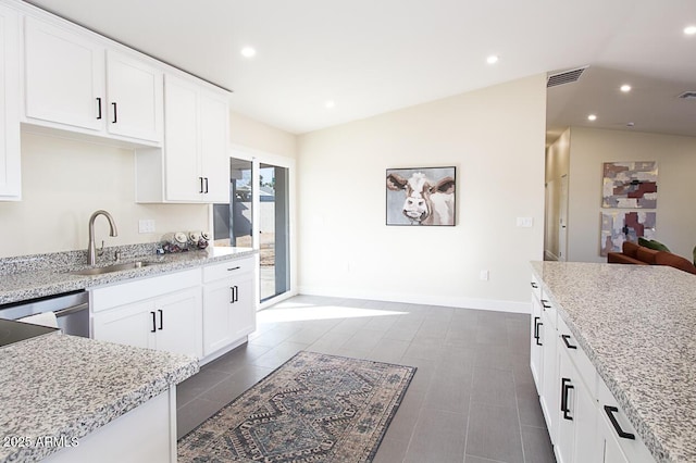 kitchen with lofted ceiling, light stone countertops, sink, and white cabinets