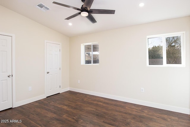 spare room with lofted ceiling, dark wood-type flooring, a wealth of natural light, and ceiling fan