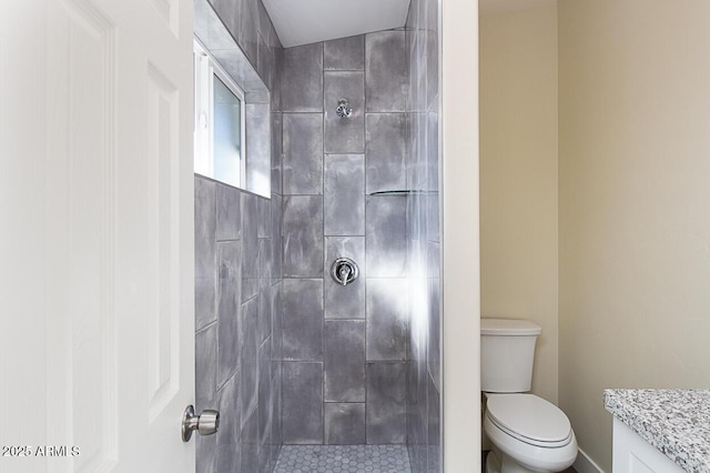 bathroom featuring vanity, tiled shower, and toilet