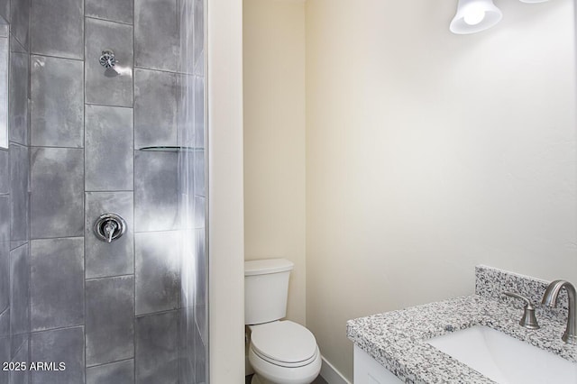 bathroom with vanity, toilet, and a tile shower