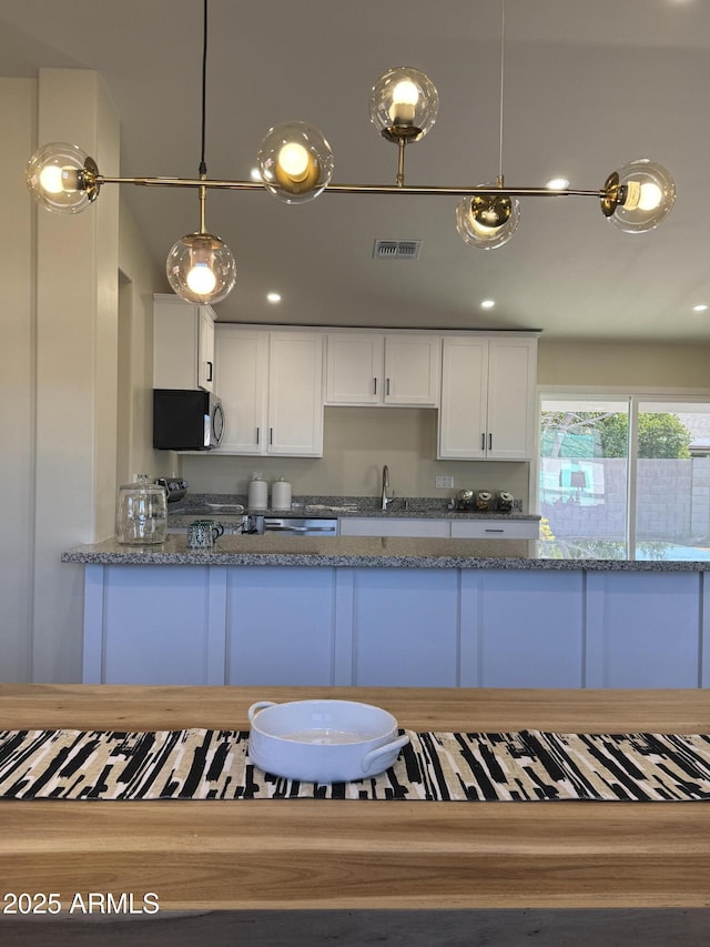 kitchen featuring sink, white cabinets, hanging light fixtures, stove, and light stone countertops