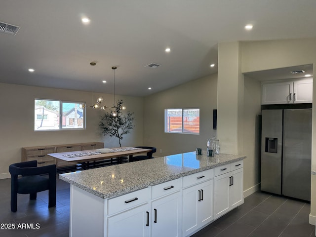 kitchen with light stone countertops, decorative light fixtures, white cabinets, and stainless steel fridge with ice dispenser