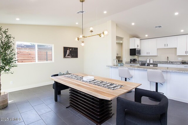 tiled dining area featuring lofted ceiling and sink