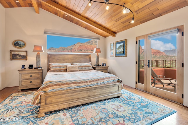 bedroom with vaulted ceiling with beams, light wood-type flooring, wooden ceiling, a mountain view, and access to exterior