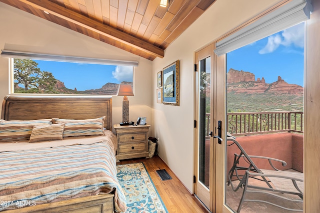 bedroom with lofted ceiling with beams, access to exterior, wood ceiling, light hardwood / wood-style floors, and a mountain view