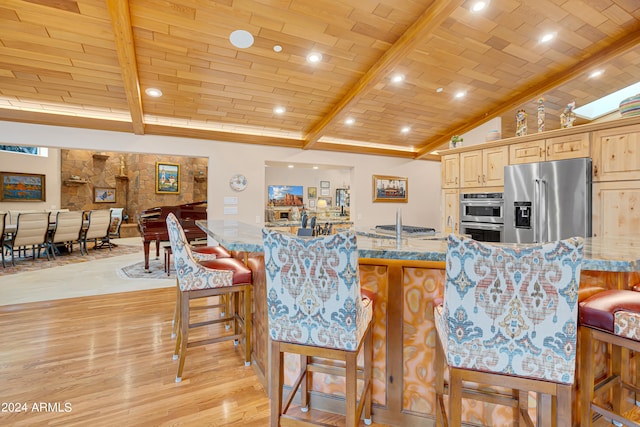 kitchen featuring brick ceiling, stainless steel appliances, light stone counters, light hardwood / wood-style floors, and light brown cabinets