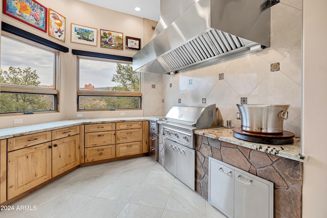 kitchen featuring island exhaust hood, light tile patterned floors, backsplash, and light stone counters