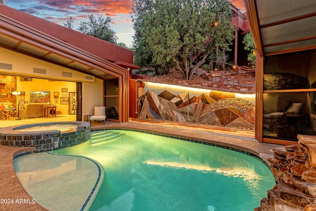 pool at dusk featuring an in ground hot tub