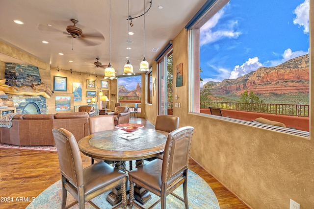 dining space with hardwood / wood-style flooring, ceiling fan, a fireplace, and a mountain view