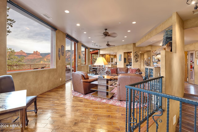 living room with wood-type flooring, a mountain view, and ceiling fan