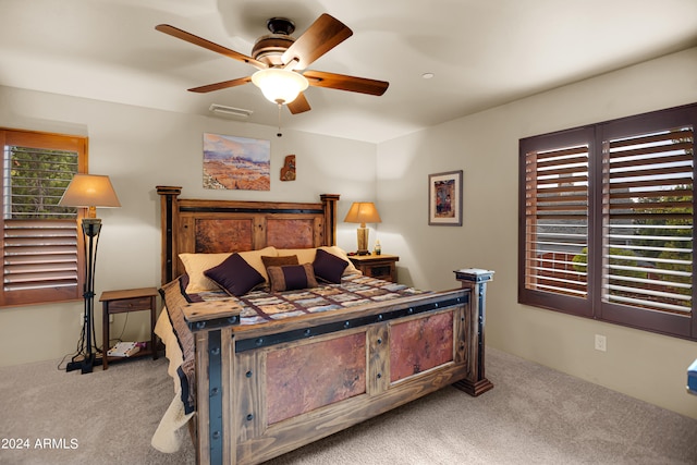 carpeted bedroom featuring multiple windows and ceiling fan