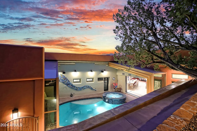 pool at dusk featuring a jacuzzi