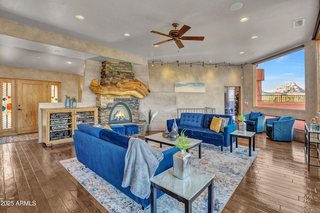 living room featuring a fireplace, dark wood-type flooring, ceiling fan, and track lighting