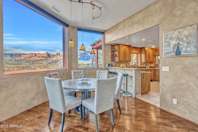 dining area featuring rail lighting, a mountain view, and light hardwood / wood-style floors