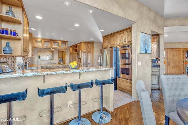 kitchen with a breakfast bar, appliances with stainless steel finishes, kitchen peninsula, and sink