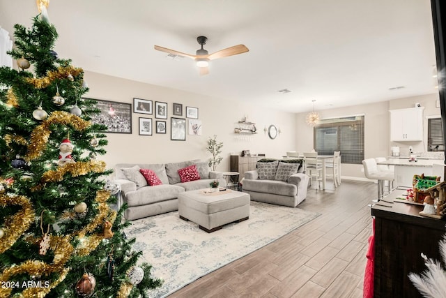 living room with ceiling fan with notable chandelier and light hardwood / wood-style floors