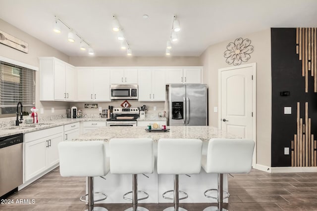 kitchen with wood-type flooring, appliances with stainless steel finishes, a center island, and sink