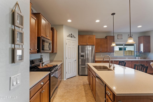 kitchen with stainless steel appliances, sink, a kitchen island with sink, and decorative light fixtures