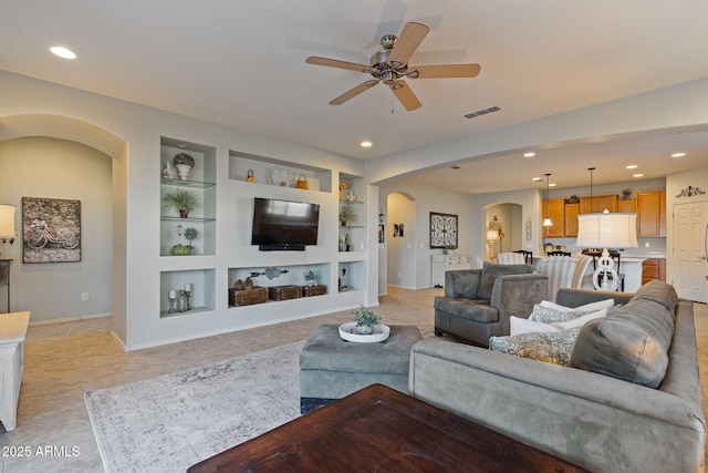 living room featuring built in shelves and ceiling fan