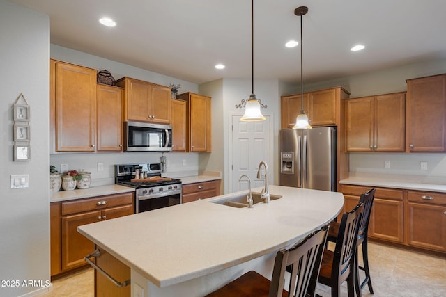 kitchen with sink, a breakfast bar area, decorative light fixtures, an island with sink, and stainless steel appliances