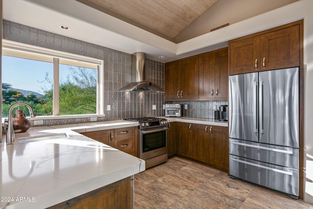 kitchen with vaulted ceiling, appliances with stainless steel finishes, sink, backsplash, and wall chimney exhaust hood