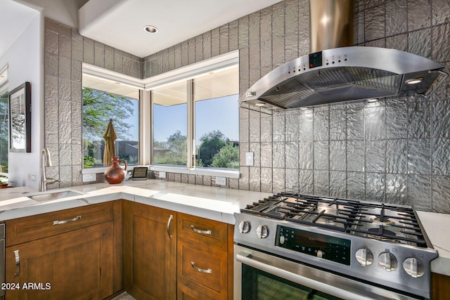 kitchen with sink, stainless steel gas range, extractor fan, and decorative backsplash