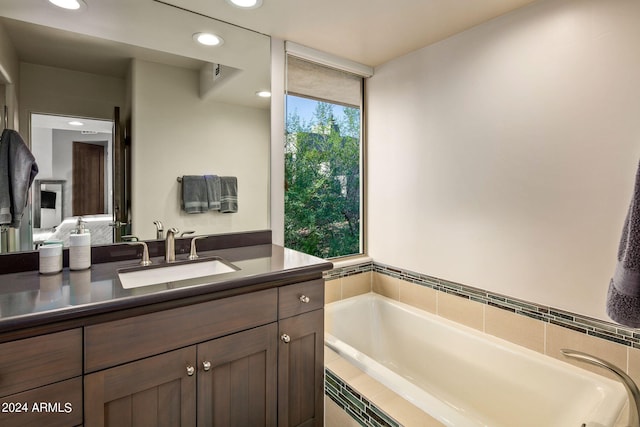 bathroom featuring vanity and tiled bath