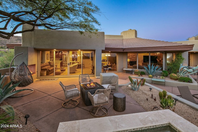 back house at dusk featuring a patio area and a fire pit