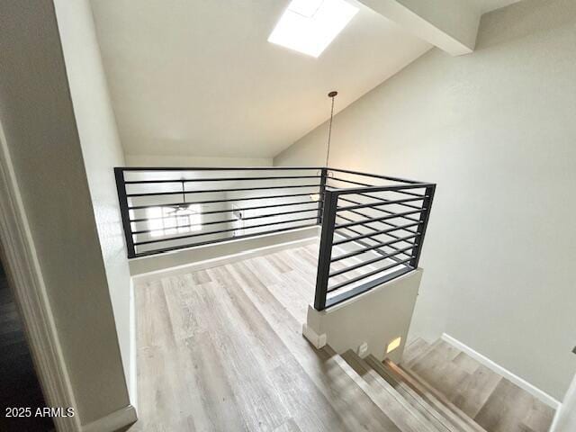 staircase featuring baseboards, wood finished floors, and vaulted ceiling with beams