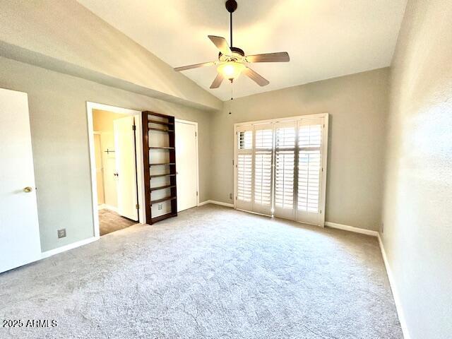 interior space featuring baseboards, lofted ceiling, carpet flooring, and a ceiling fan