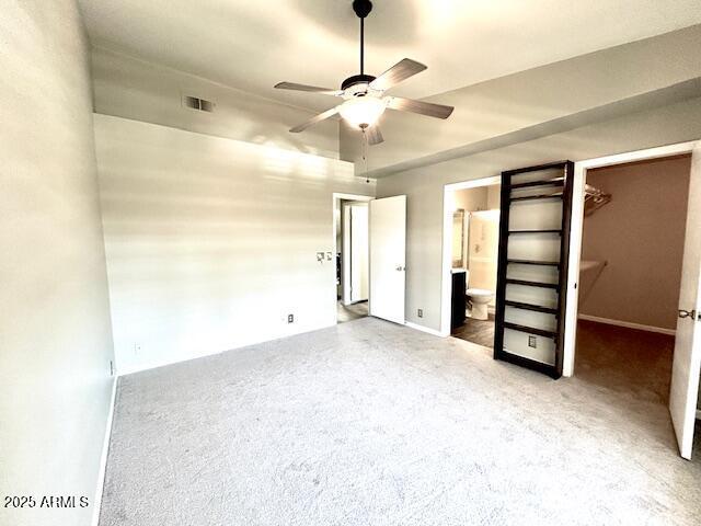 unfurnished bedroom featuring visible vents, ensuite bathroom, a closet, carpet, and a spacious closet