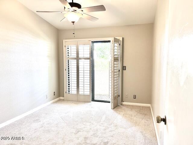 carpeted empty room featuring baseboards and ceiling fan