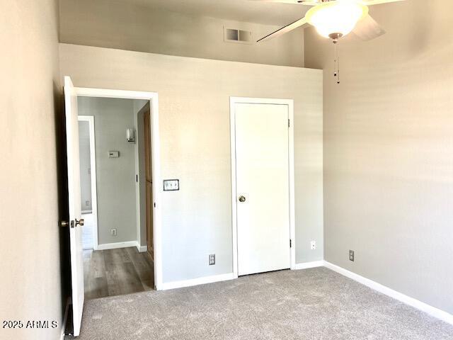 unfurnished bedroom featuring a ceiling fan, visible vents, carpet, and baseboards