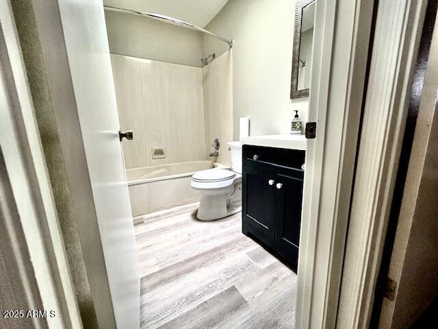 full bath featuring shower / bathing tub combination, toilet, wood finished floors, and vanity