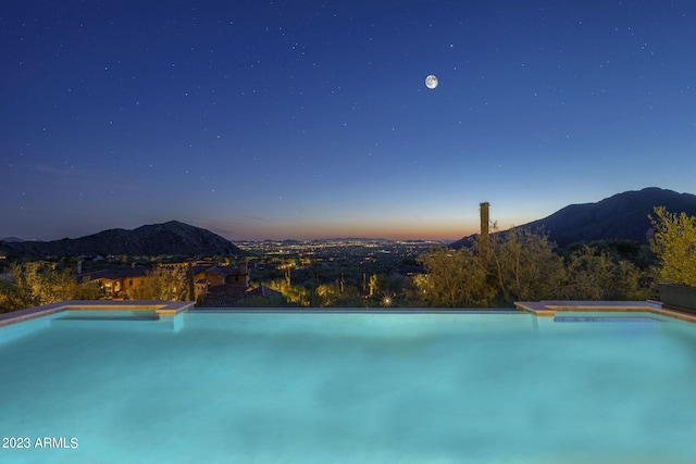 pool at dusk featuring a mountain view