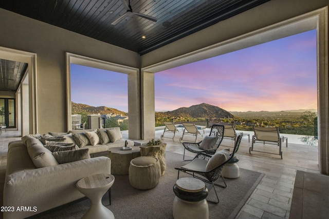 patio terrace at dusk with ceiling fan, a mountain view, and outdoor lounge area