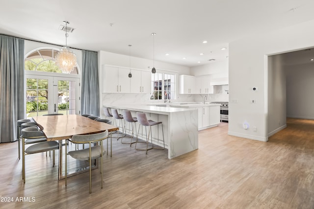 kitchen featuring white cabinetry, light hardwood / wood-style flooring, and hanging light fixtures