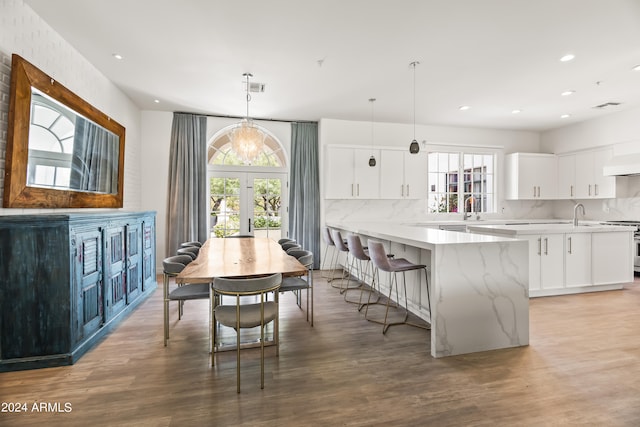 kitchen with white cabinets, a wealth of natural light, hardwood / wood-style flooring, and hanging light fixtures