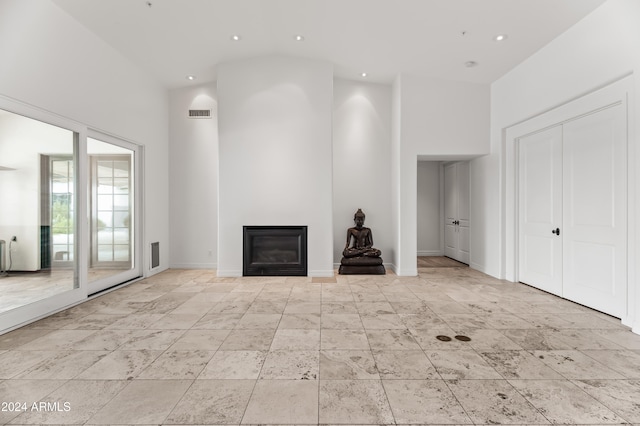 unfurnished living room featuring a towering ceiling