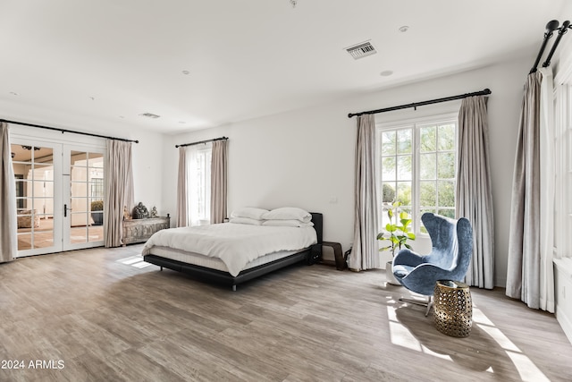 bedroom featuring access to exterior, french doors, and light hardwood / wood-style flooring