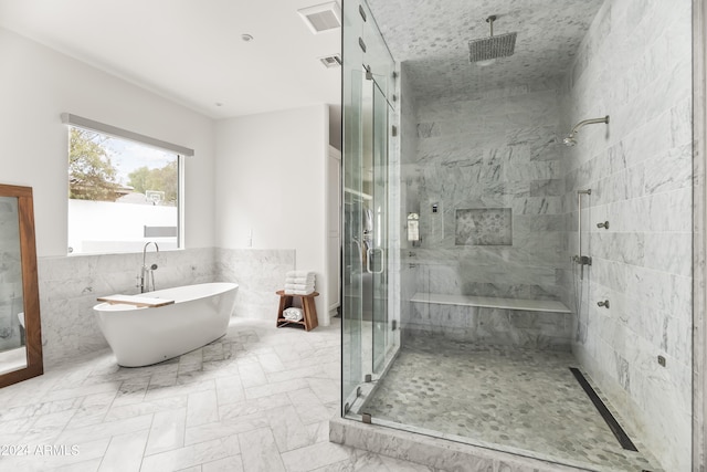 bathroom featuring plus walk in shower and tile walls